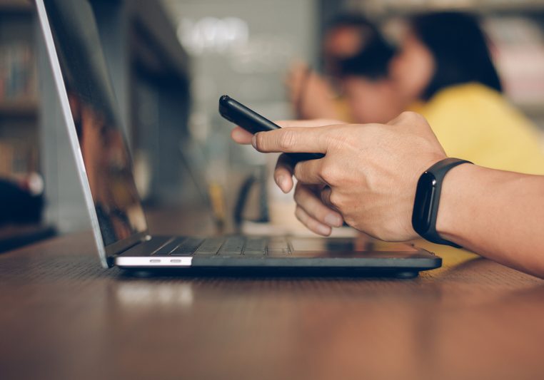 Businessman using laptop and typing on mobile smart phone