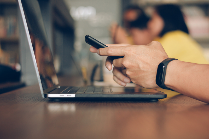 Businessman using laptop and typing on mobile smart phone